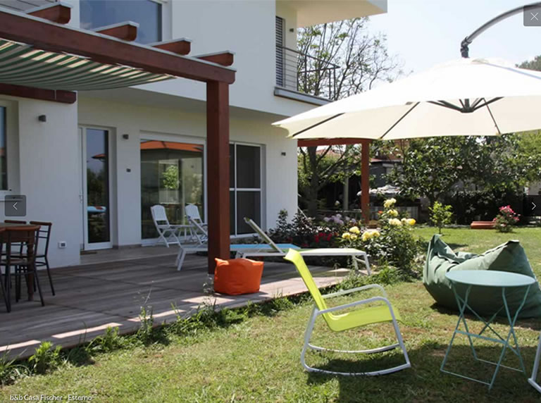 A cozy patio with modern furniture, sun umbrella, and a garden filled with flowers outside the b&b.